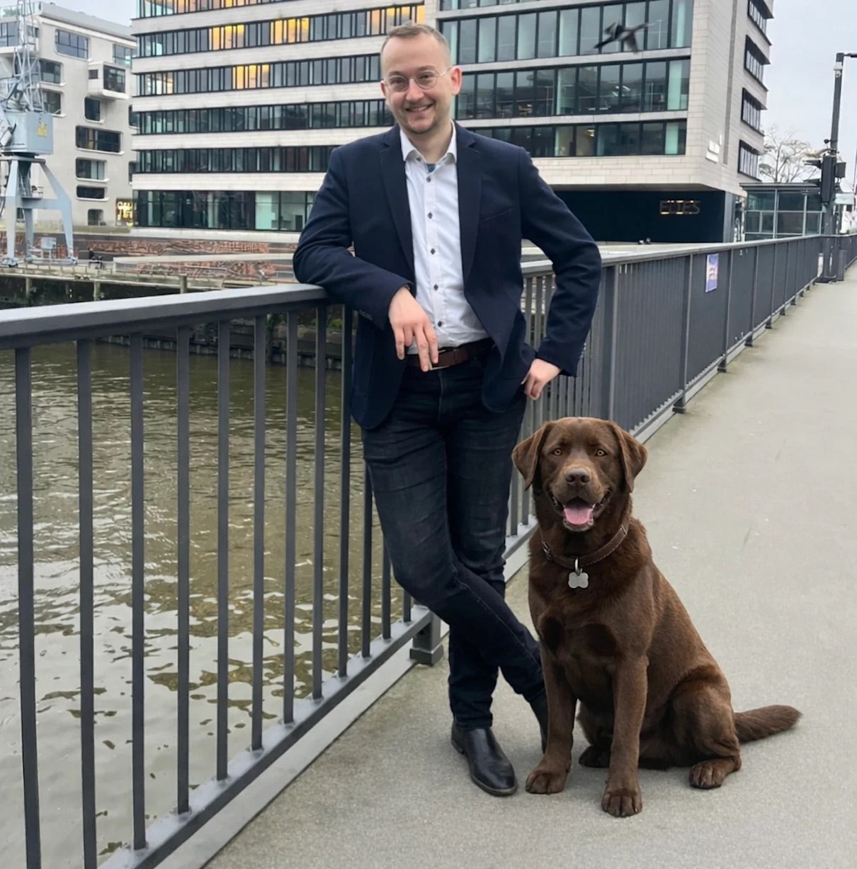 Marvin, Gründer von Pfotenmarkt, mit braunem Labrador am Wasser in Hamburg
